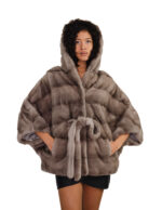 Накидка из серебристо-голубой норки 48/54 с горизонтальной отделкой по всей поверхности, капюшоном и внутренним поясом на талии.